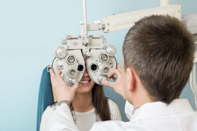 Optometrist überprüft das Sehvermögen einer lächelnden Patientin.