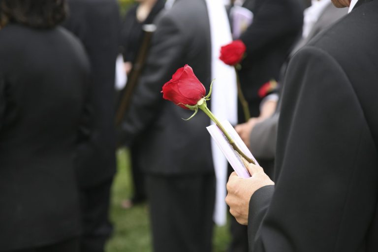 Eine Gruppe von Menschen in Schwarz, einige halten rote Rosen.