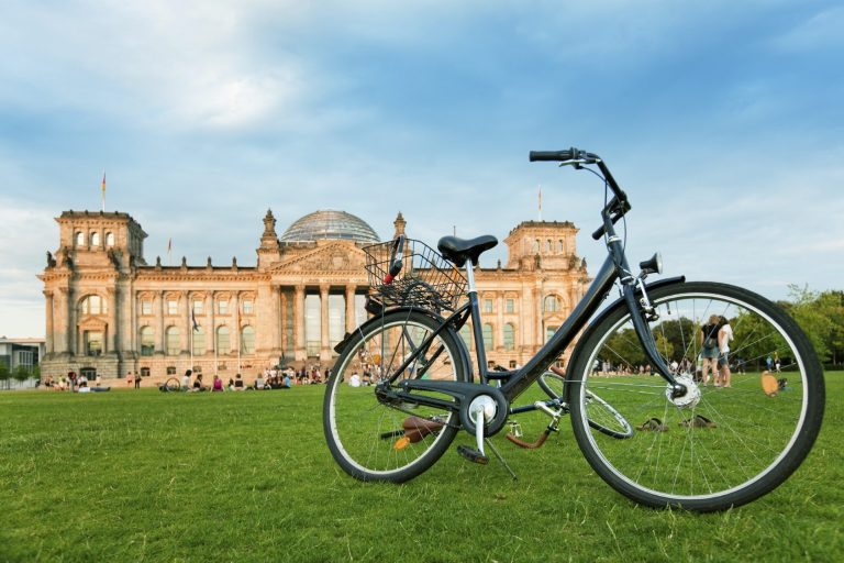 Schwarzes Fahrrad im Vordergrund mit dem Reichstagsgebäude im Hintergrund.