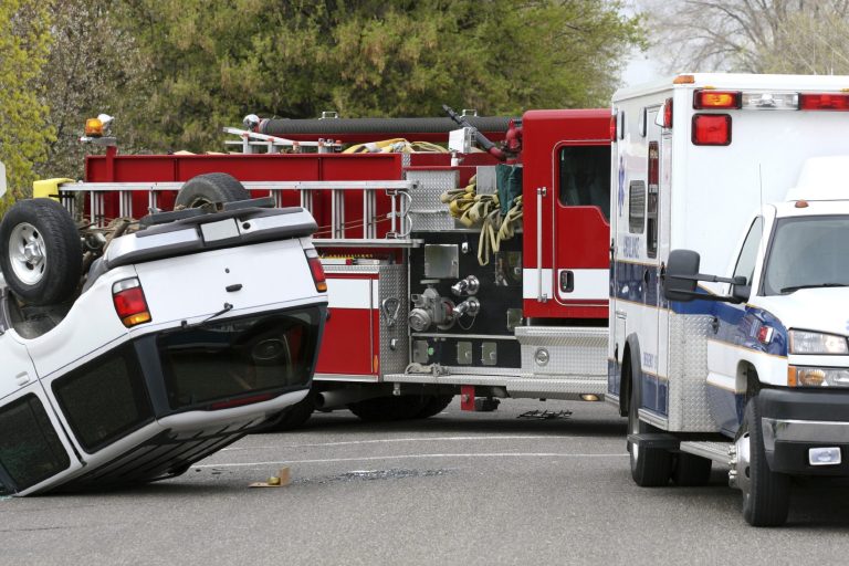 Umgekippter SUV neben einem Feuerwehrfahrzeug und einem Rettungswagen.