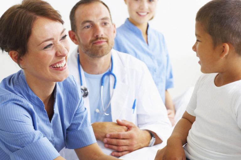 Lächelnde Ärzte und eine Krankenschwester sprechen mit einem kleinen Jungen im Krankenhaus.